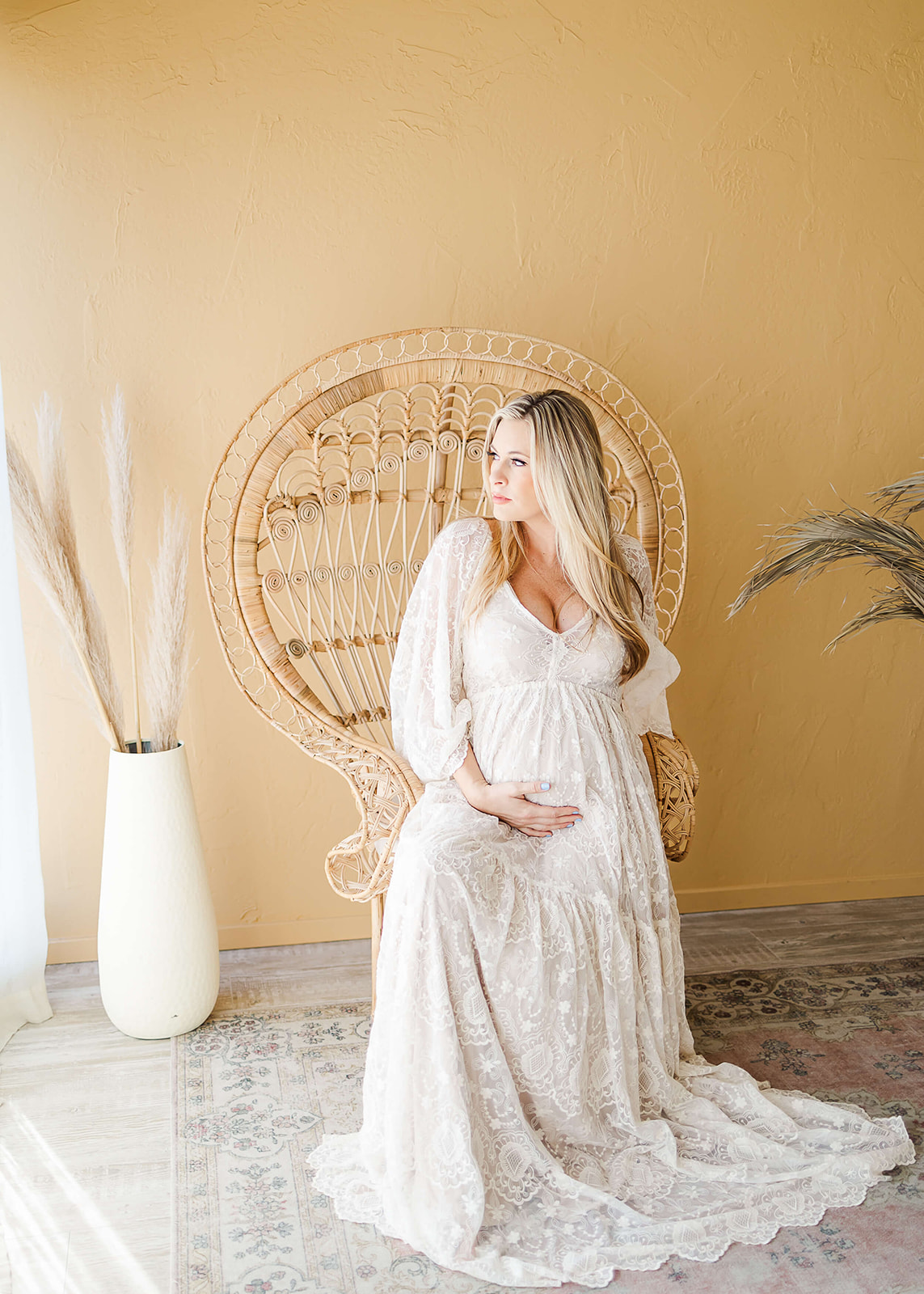 mom to be in white maternity gown sitting in a peacock chair Orange County Doulas