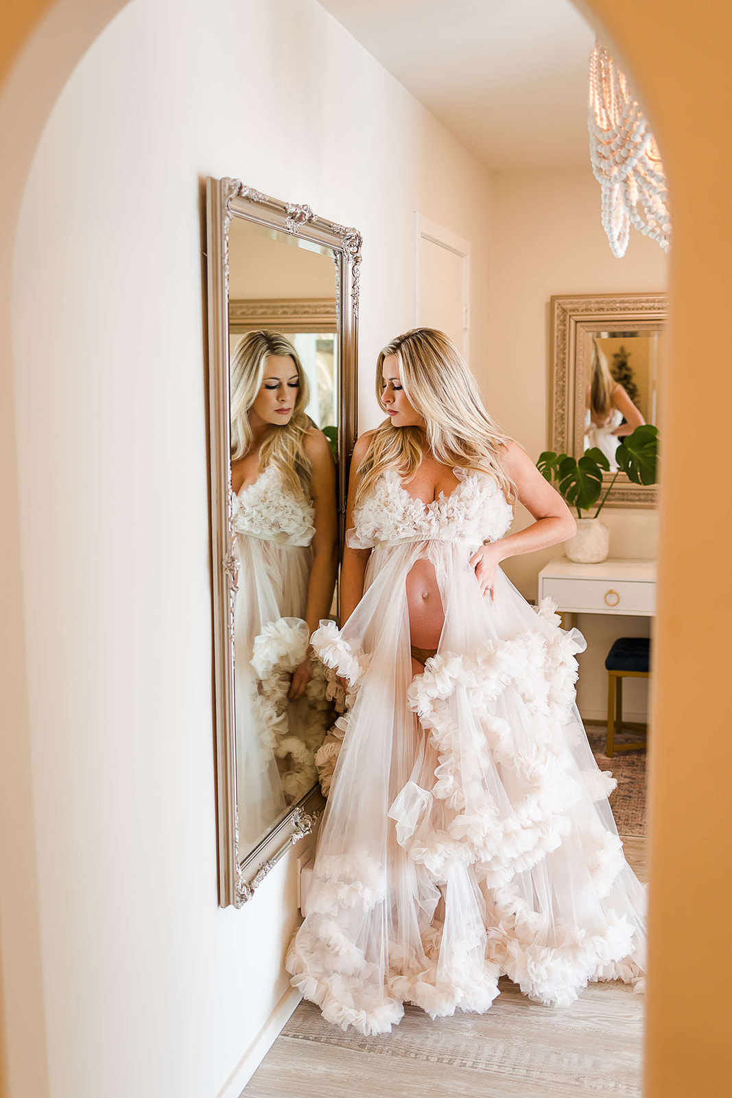 mom to be in a white open gown looking in the mirror Orange County Doulas