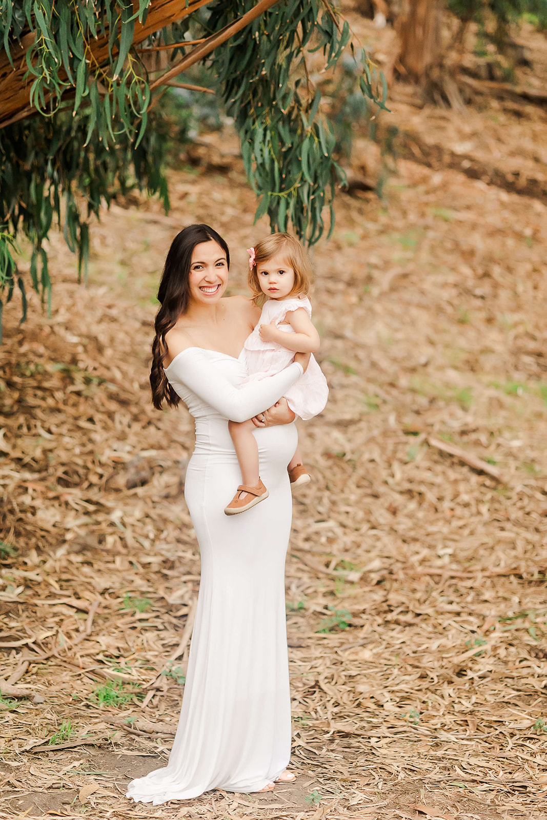 mom to be in white maternity gown holding her young daughter Orange county midwife