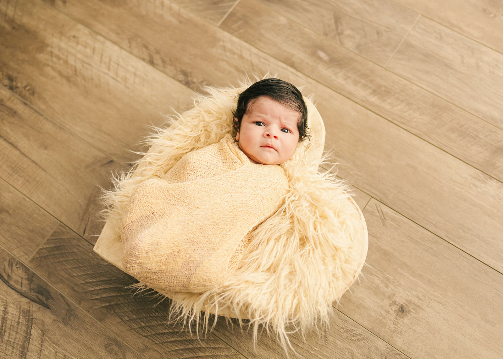 newborn baby in yellow wrap laying in a heart orange county pediatricians