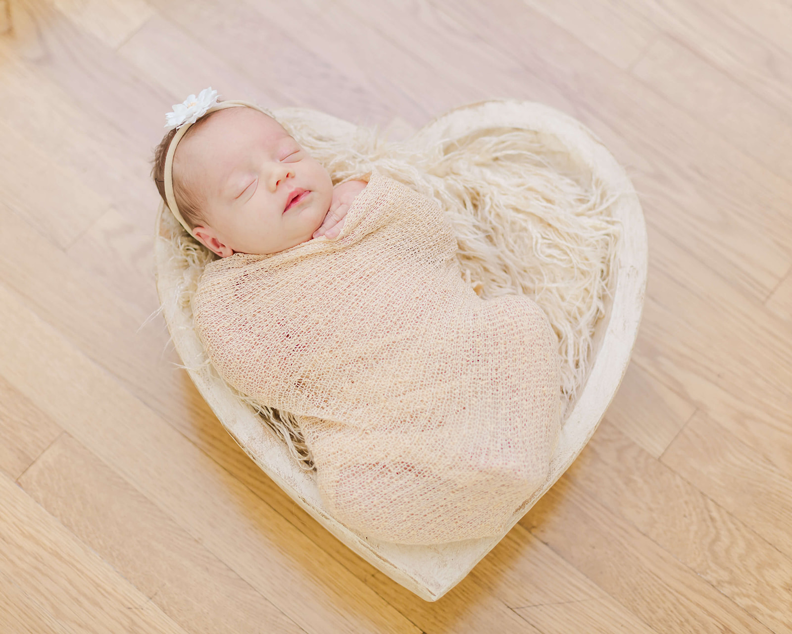 newborn girl wrapped in cream laying in a hear basket Temecula Pediatricians