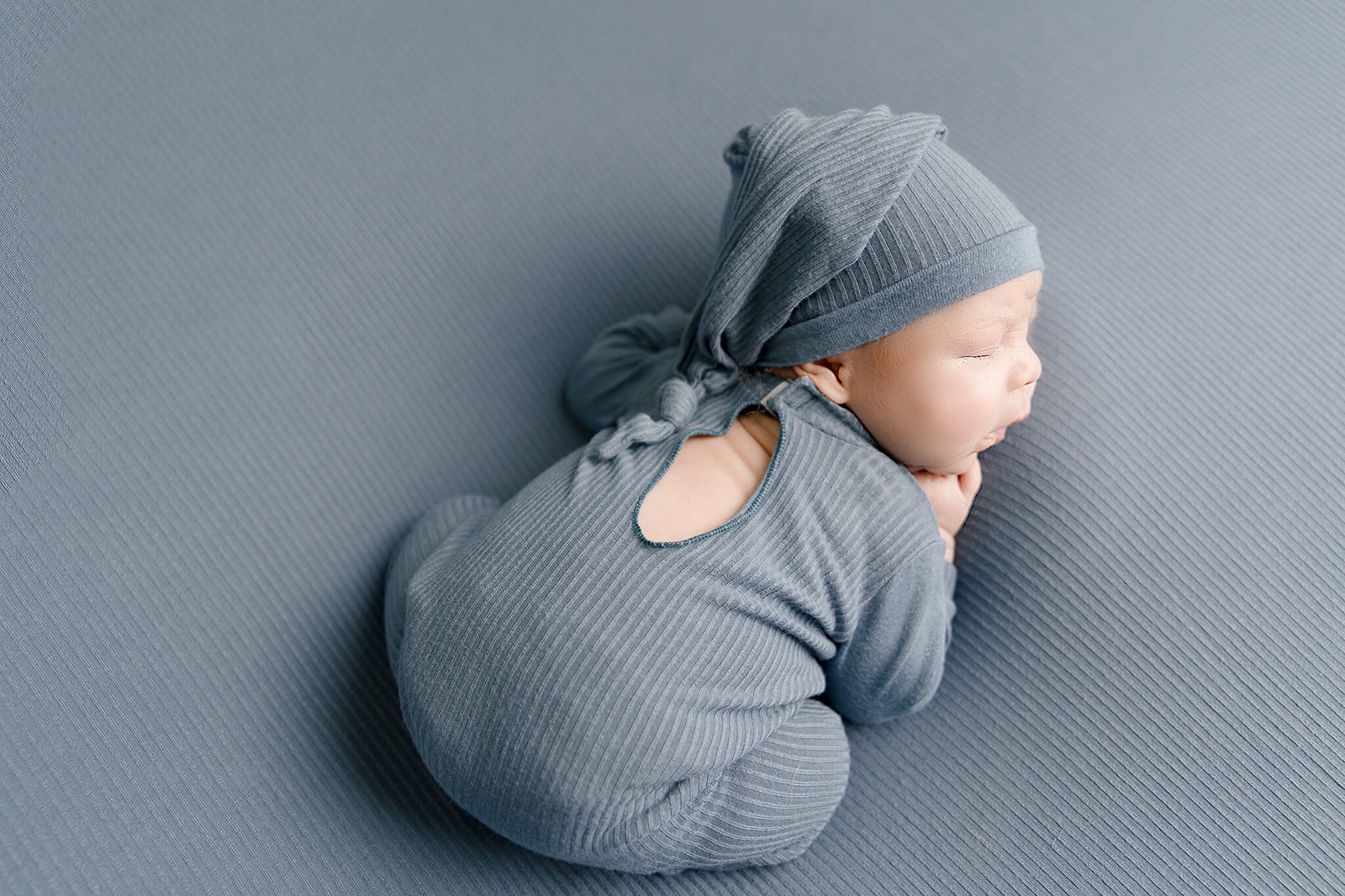 A newborn baby sleep in a blue onesie and blue sleep hat Los Angeles Doulas