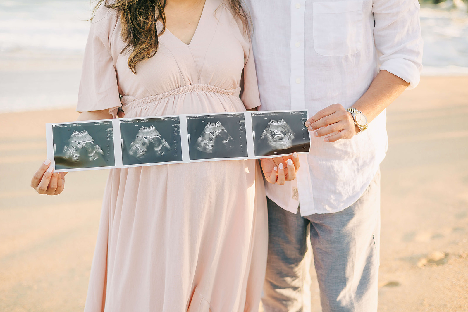 Details of a mom to be and father holding their sonograms on the beach Best Maternity Hospital in Los Angeles