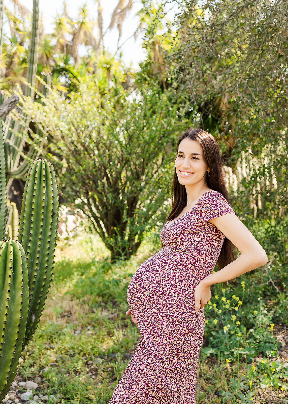 A mother-to-be stands in a trail holding her back and bump in a purple dress Lake Forest Pediatricians
