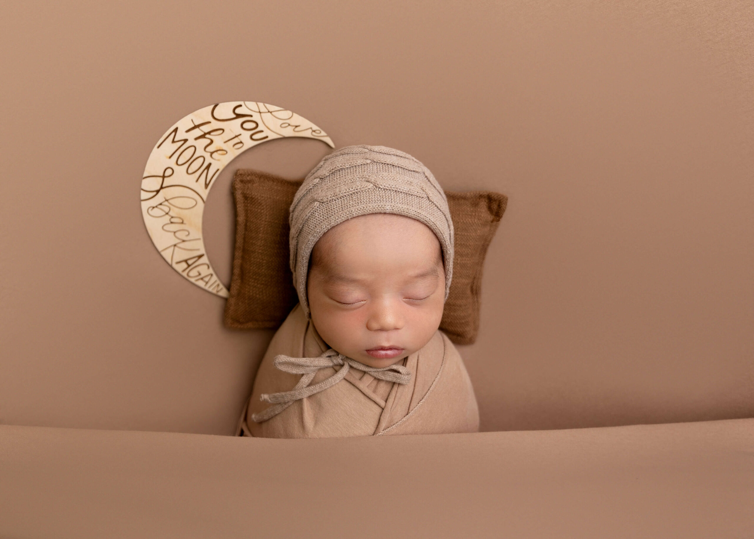 Baby posed near moon prop while being swaddled by Ashley Nicole.