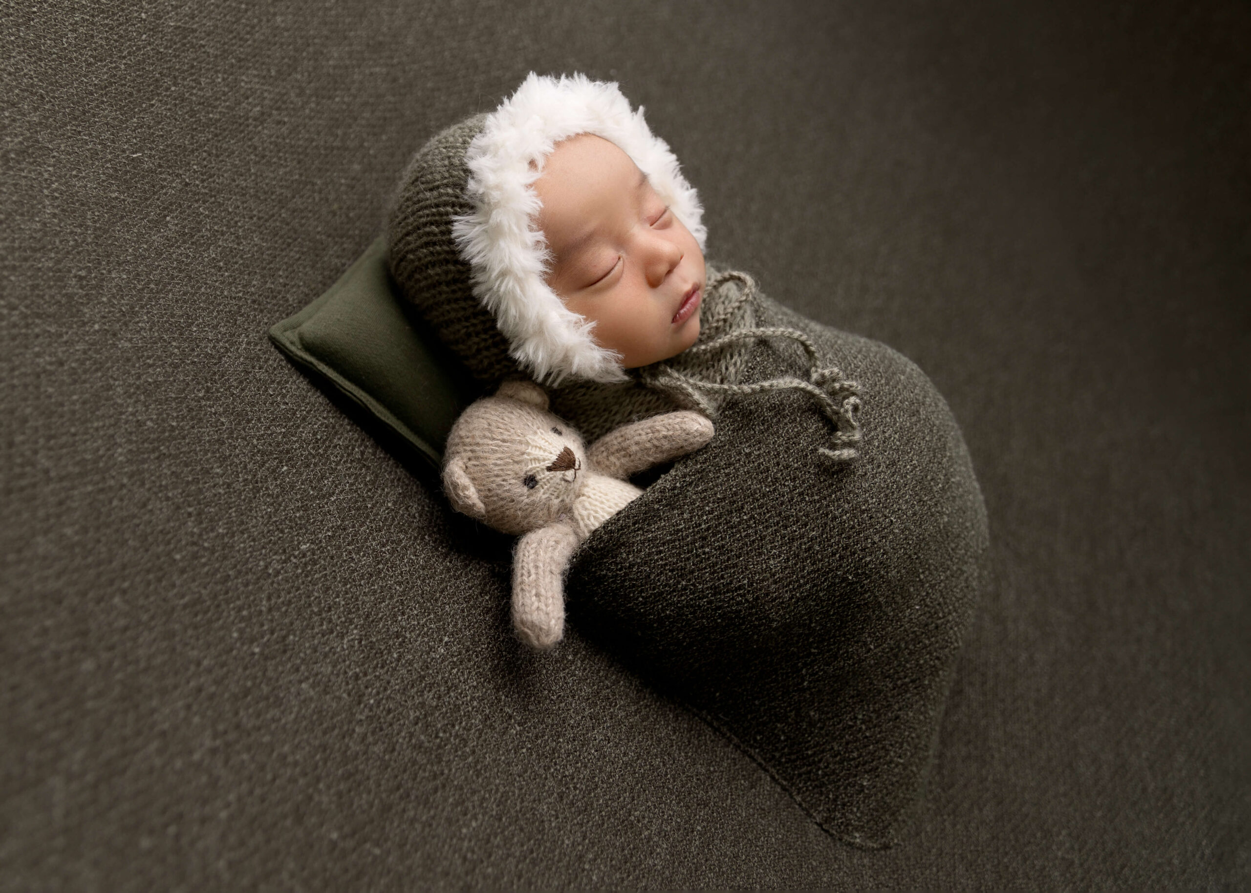 Baby posed sleeping in a pocket with a teddy bear in studio by Ashley Nicole Photography.