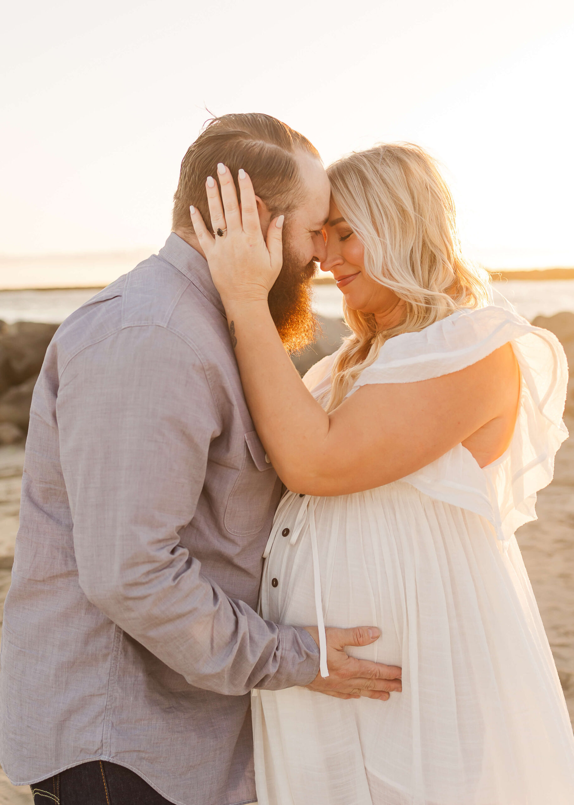 Couple embraced during maternity session at the beach in Los Angeles by Ashley Nicole.