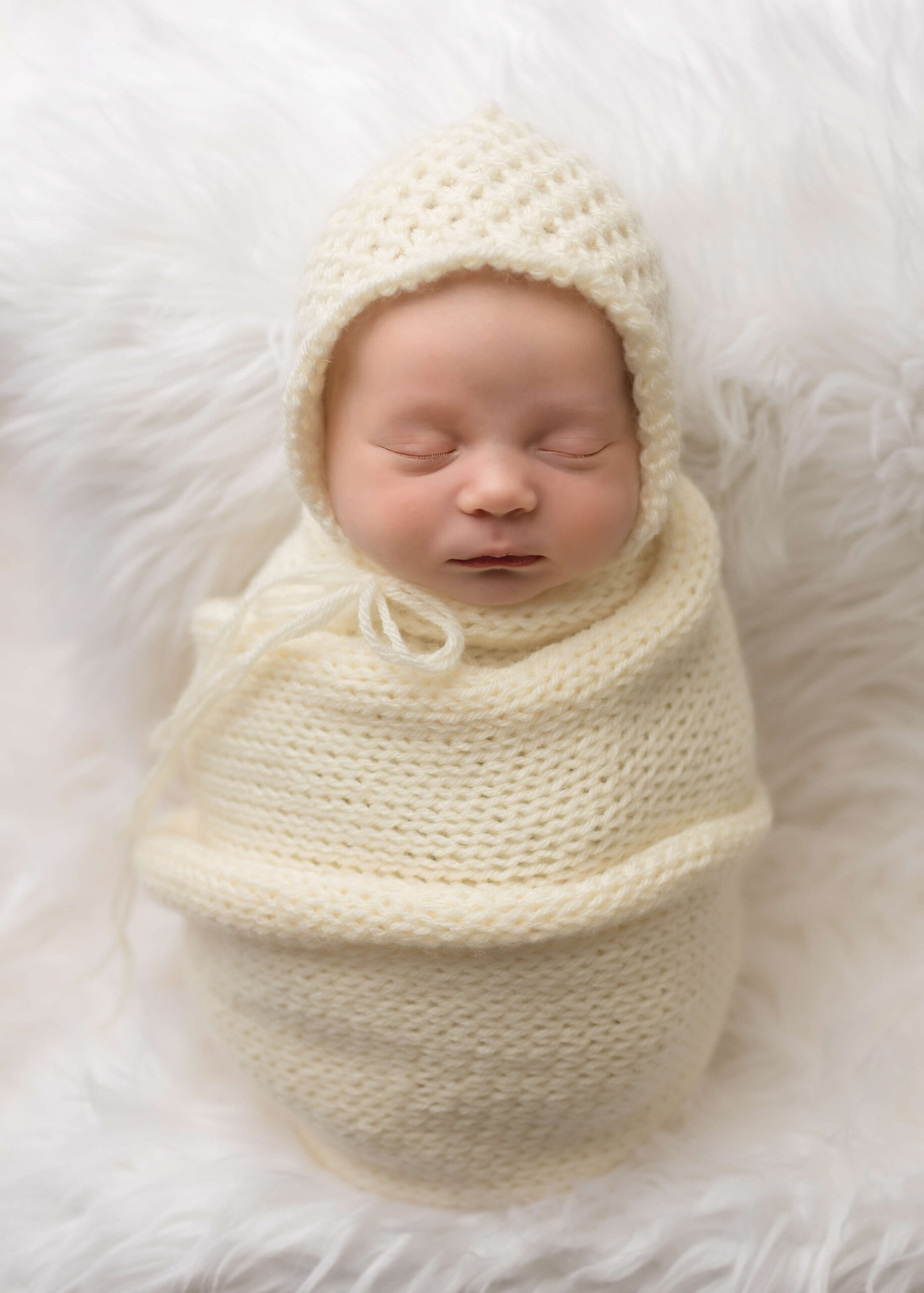 Baby wrapped in knit blanket with beanie hat posed by Ashley Nicole Photography.