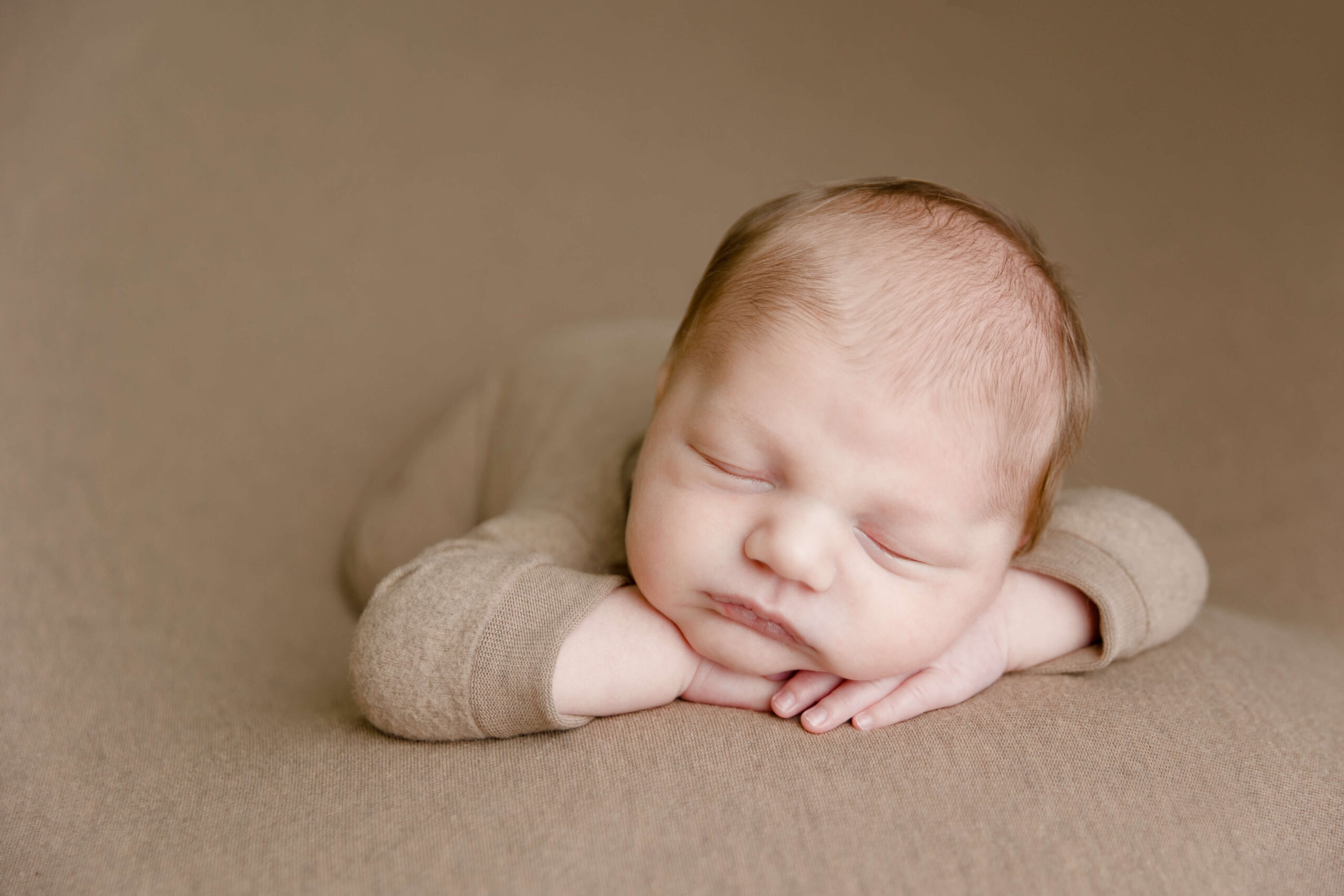 Baby boy posed chin on hands by Ashley Nicole Photography.