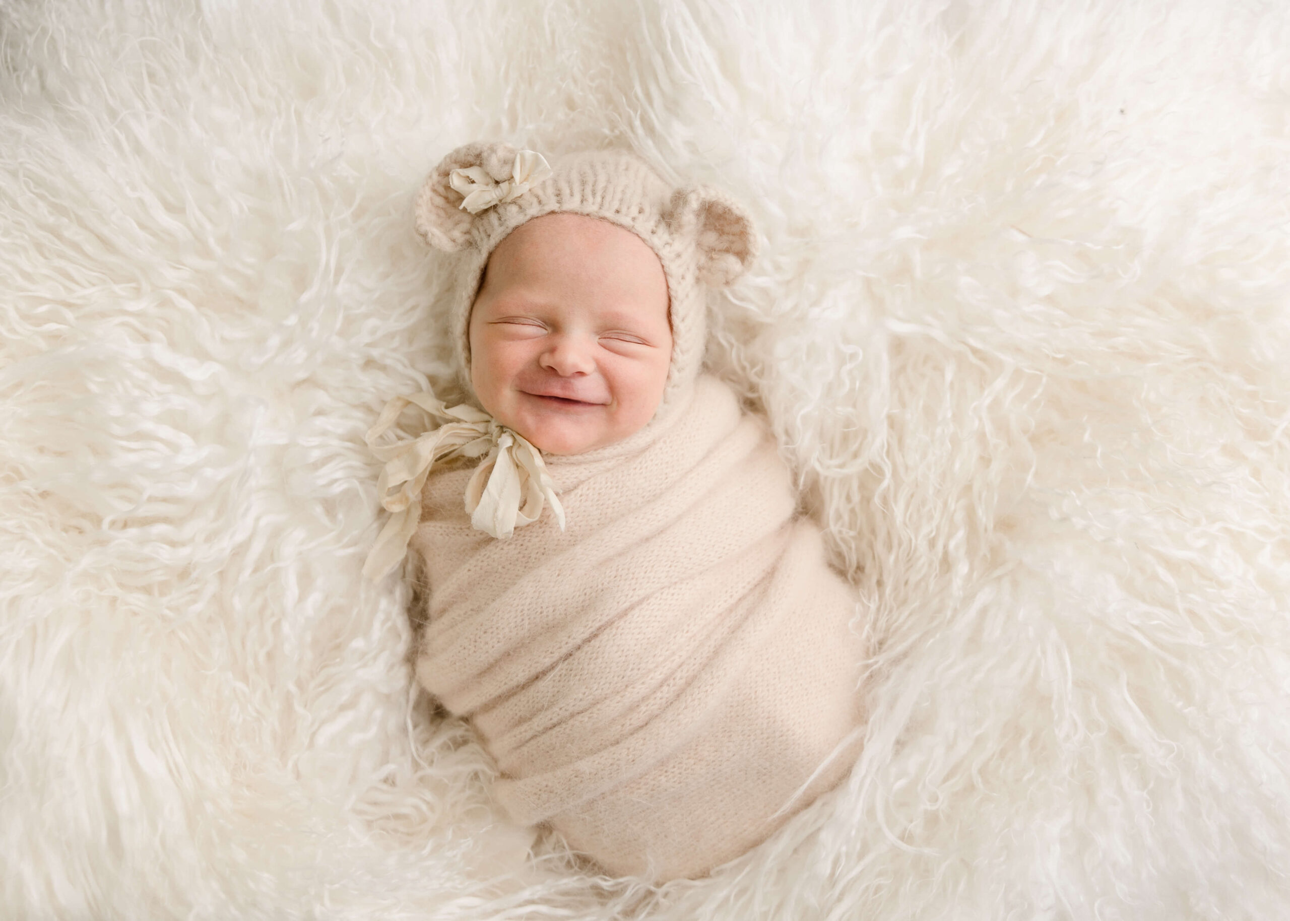 Wrapped baby smiling in studio session by Ashley Nicole Photography.