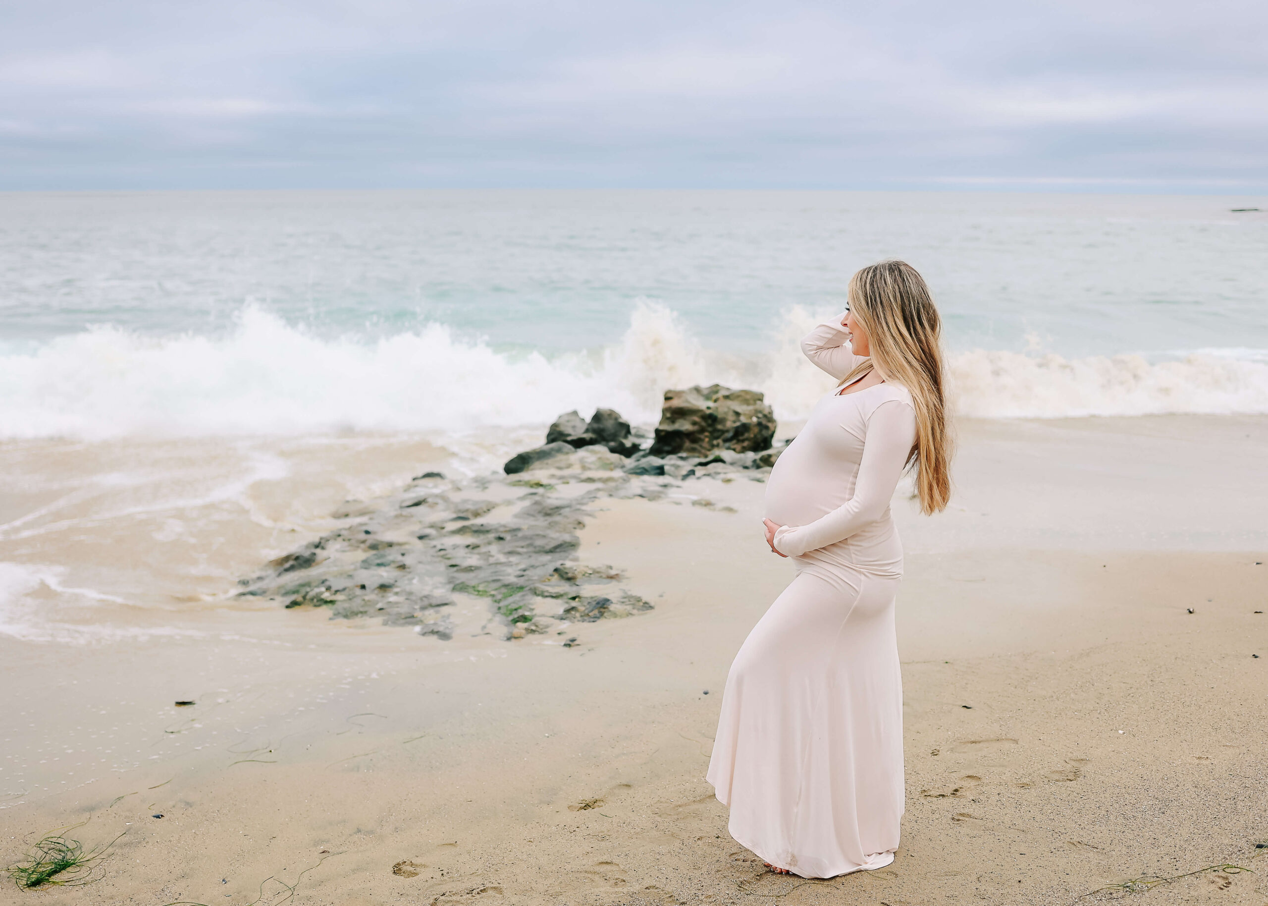 Mama looking out at the ocean in Laguna Beach while holding bump.