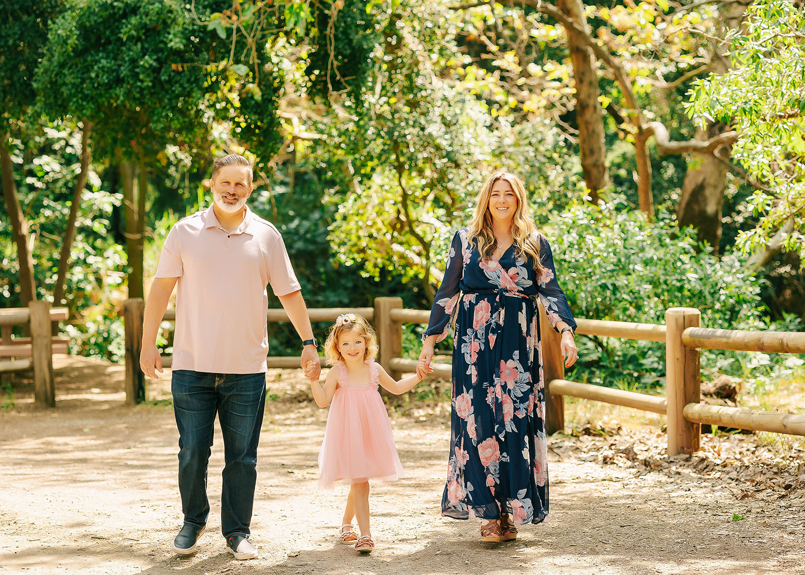 A family of three hold hands and walk down a park path Things to do in Los Angeles with Kids