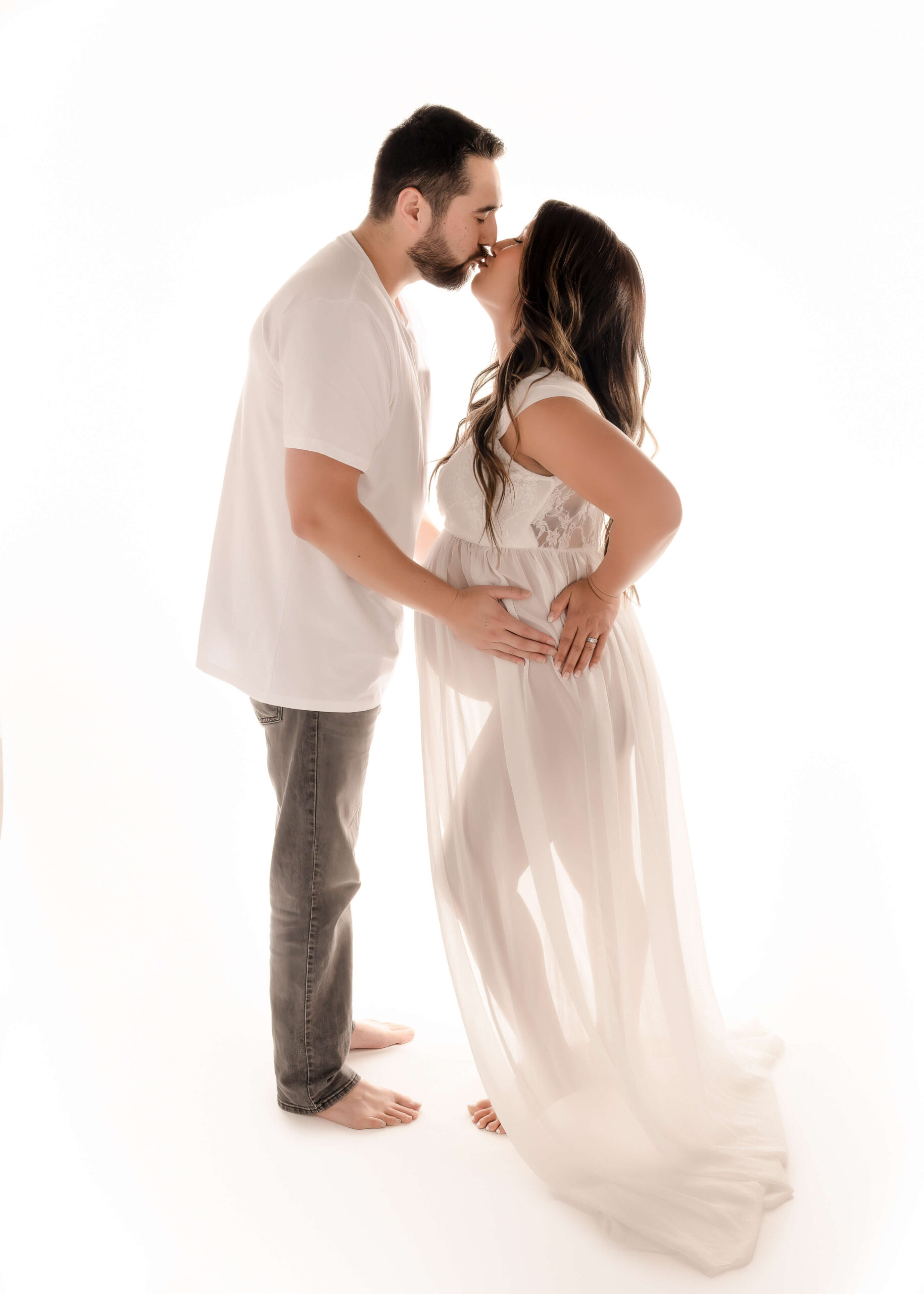 Husband and wife embraced and kissing during in studio maternity session with Ashley Nicole Photography.