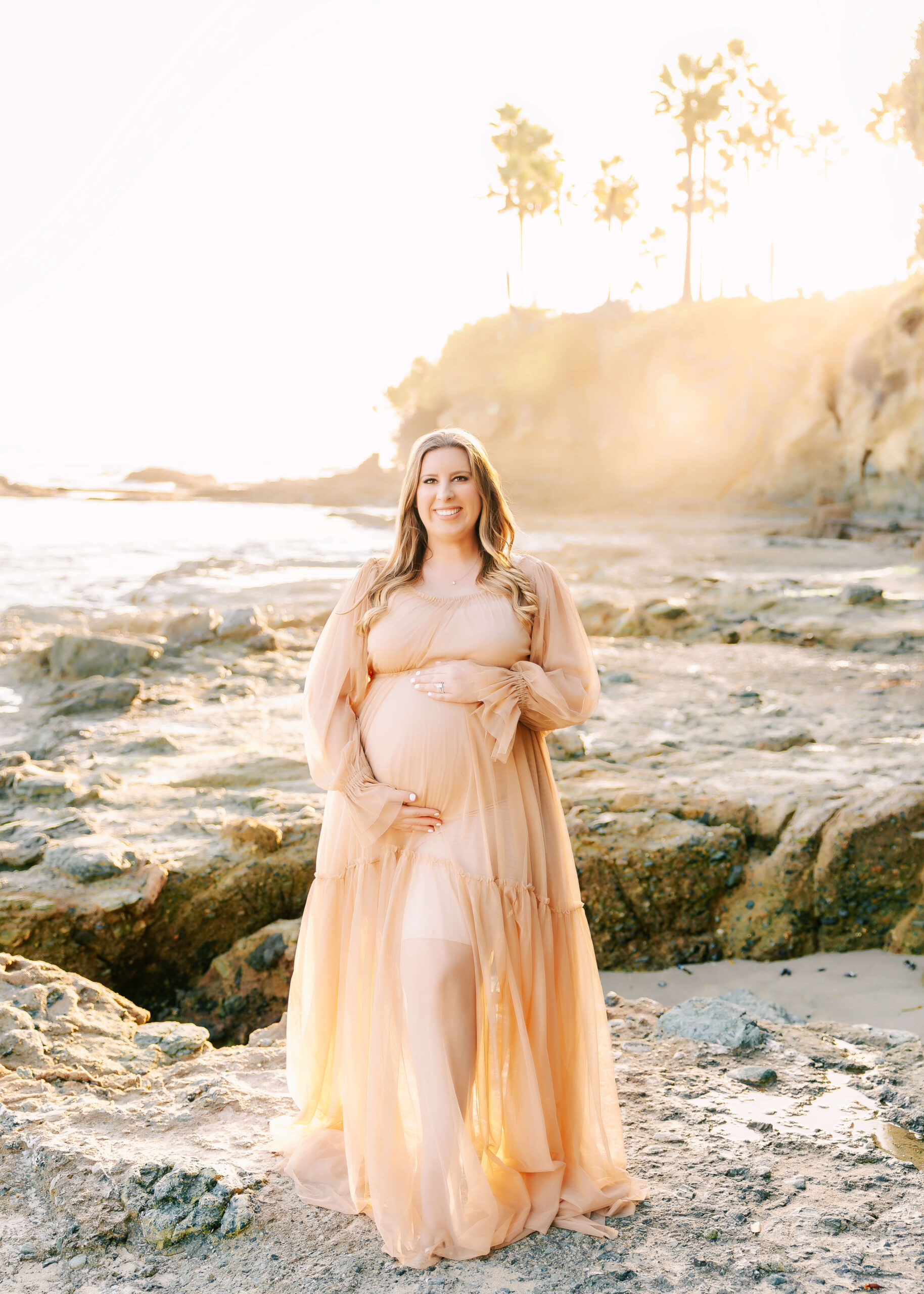 Excited Mama standing on rocks during her Laguna Beach Maternity session.