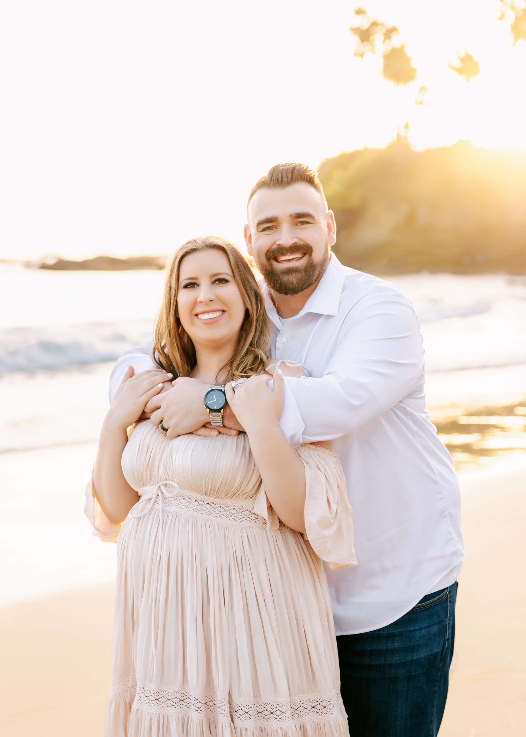 Husband hugging wife while they excitedly smile at maternity session by Ashley Nicole Photography.