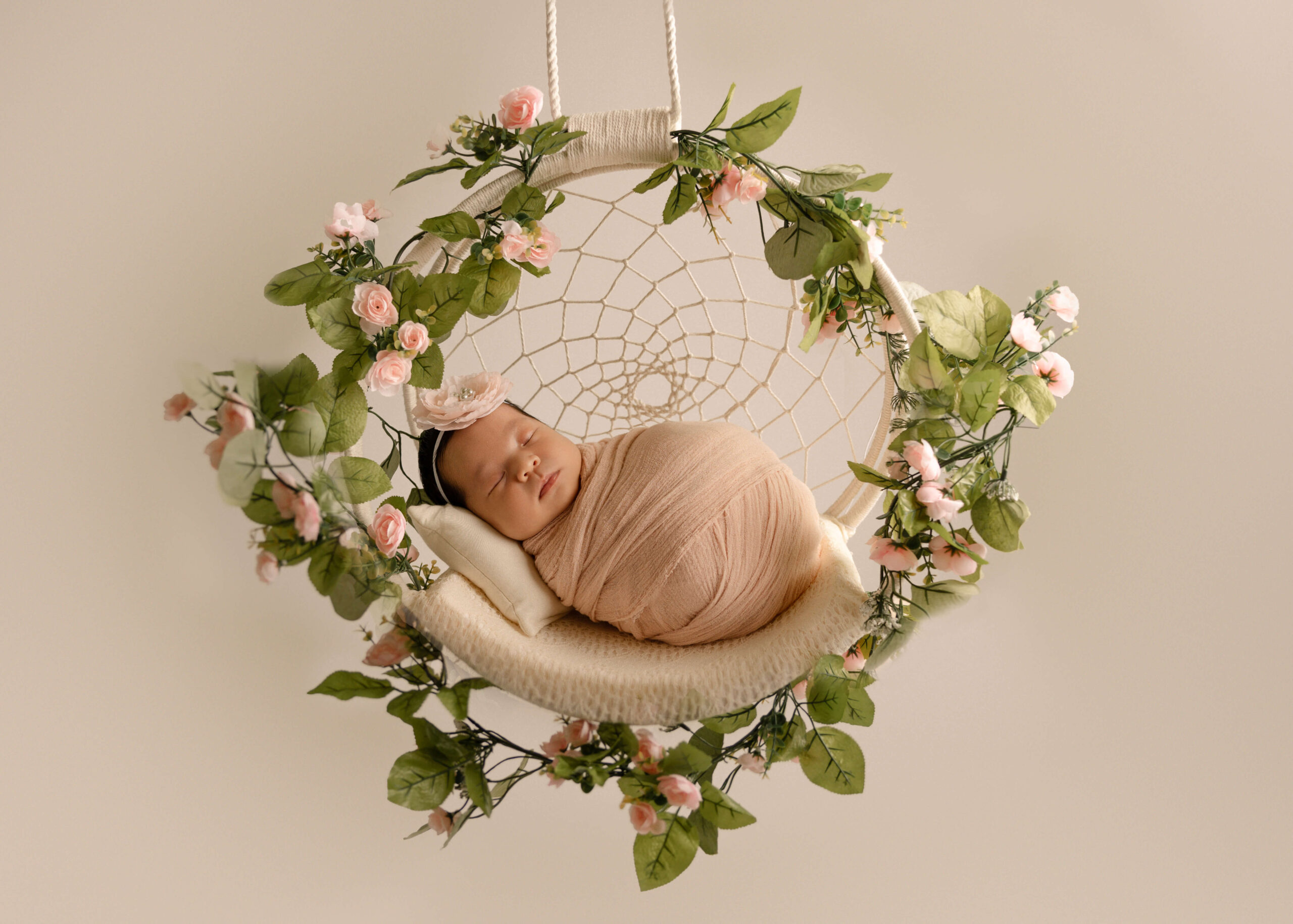 Baby sleeping wrapped in floral dream catcher in studio in Los Angeles by Ashley Nicole Photography.