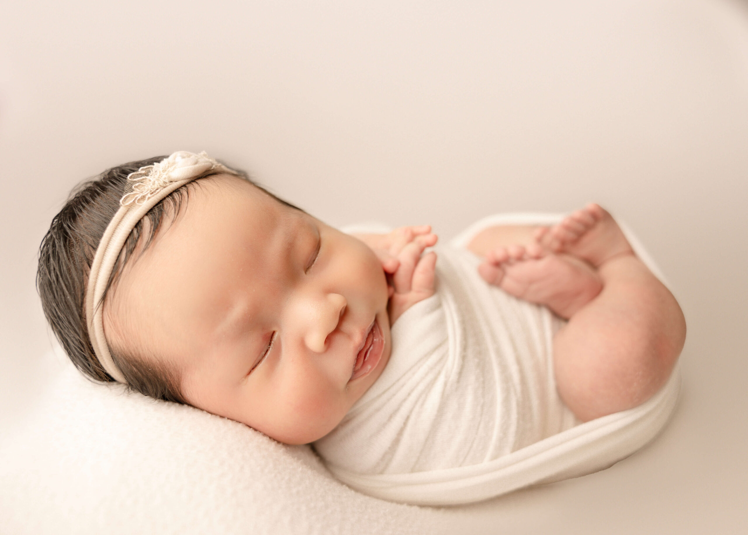 Sleeping baby wrapped in white swaddle blanket in studio Newborn session by Ashley Nicole Photography for Los Angeles Fertility Clinics.