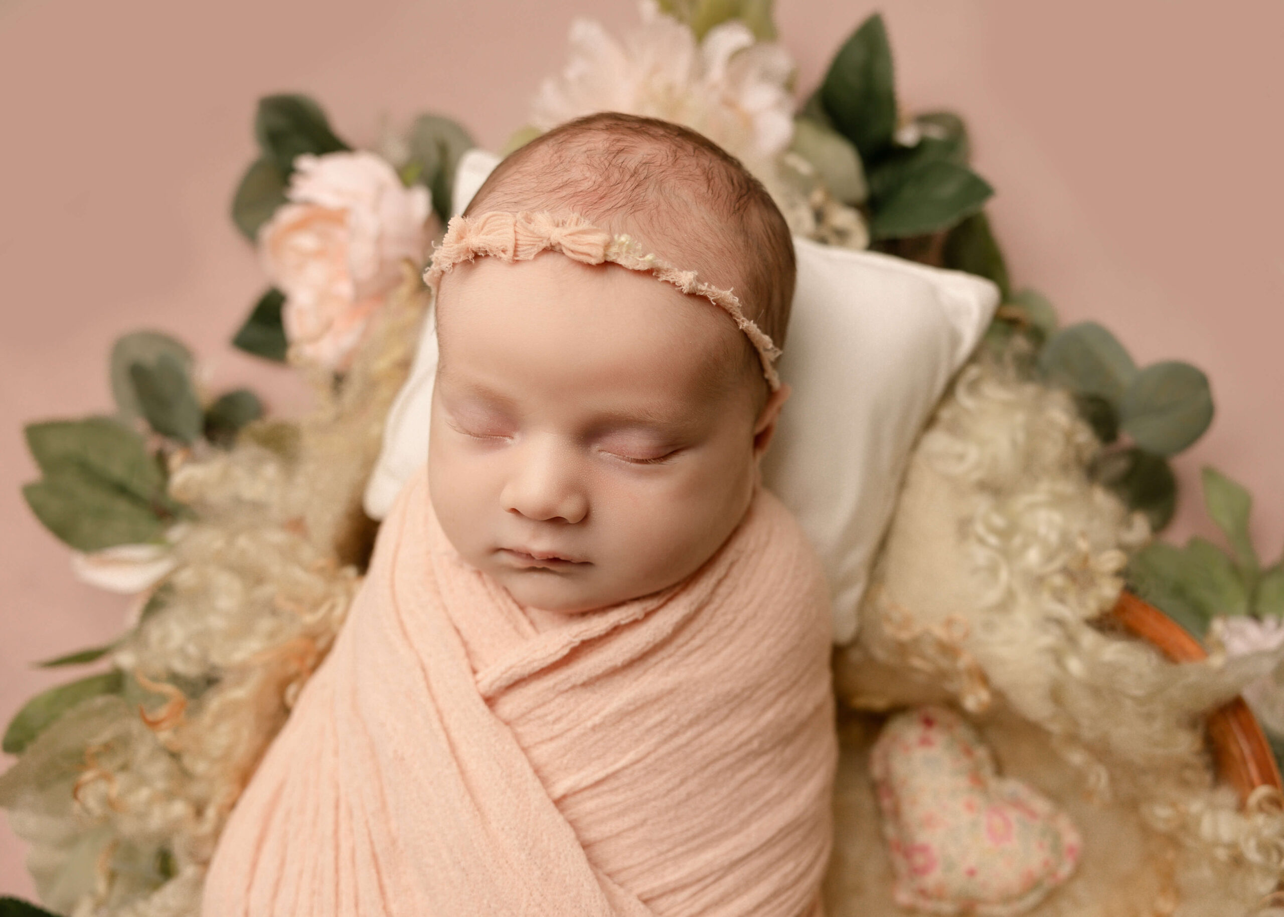 Baby girl posed in heart bowl surrounded by flowers sleeping posed by Ashley Nicole Photography.