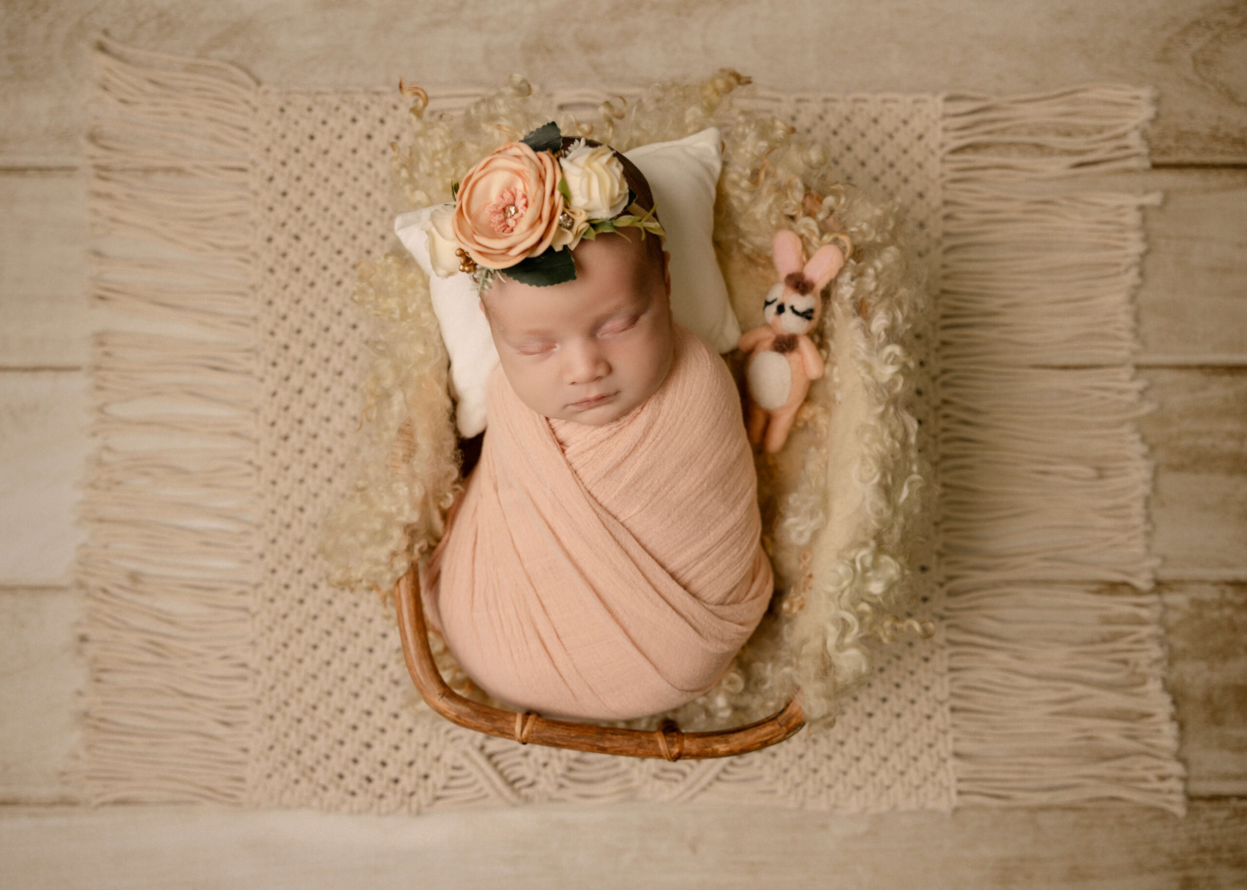 Newborn girl posed studio session in Orange County, CA by Ashley Nicole Photography. Baby posed tan basket with a rabbit stuffy.