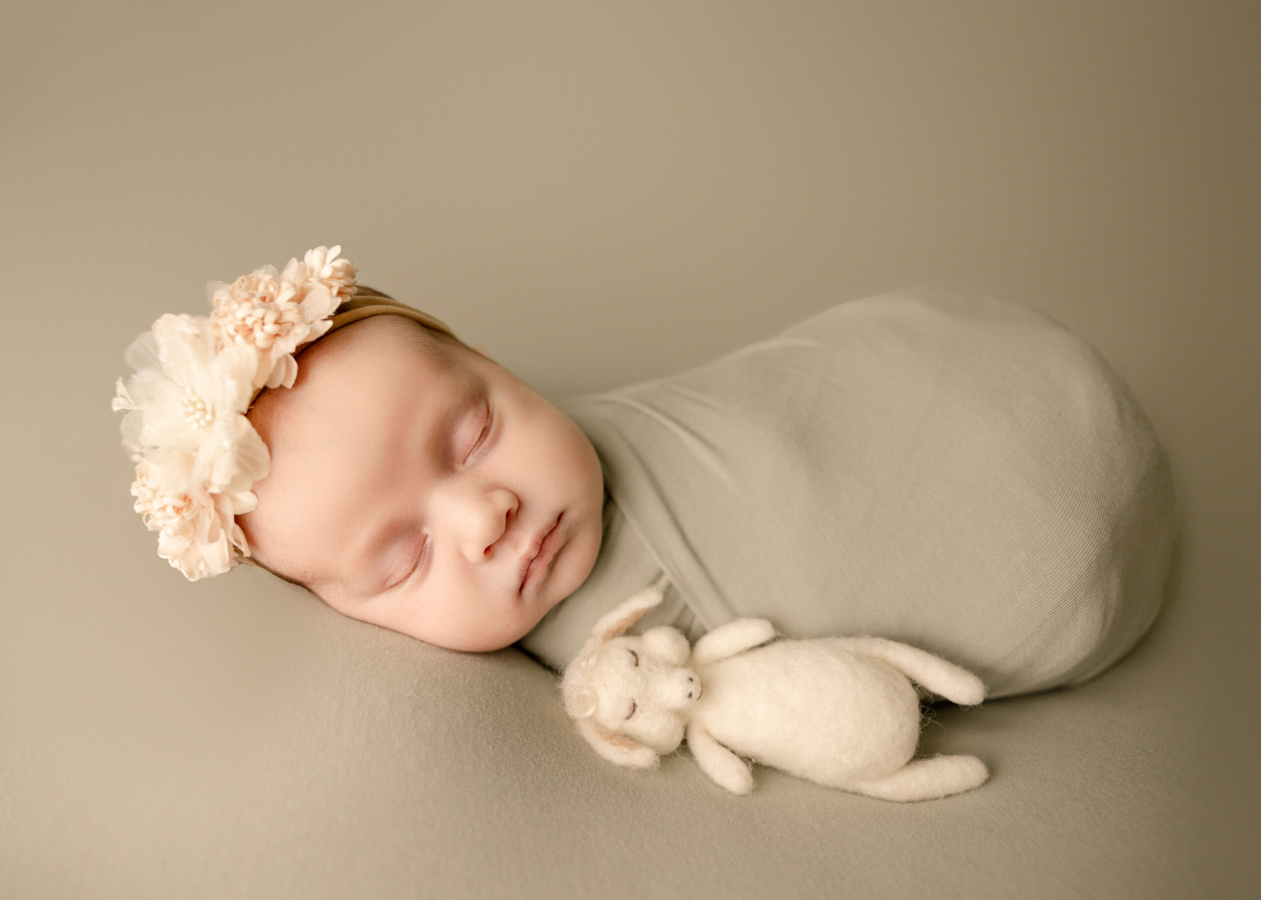 Baby sleeping on sage green blanket next to lamb stuffy in studio by Ashley Nicole.
