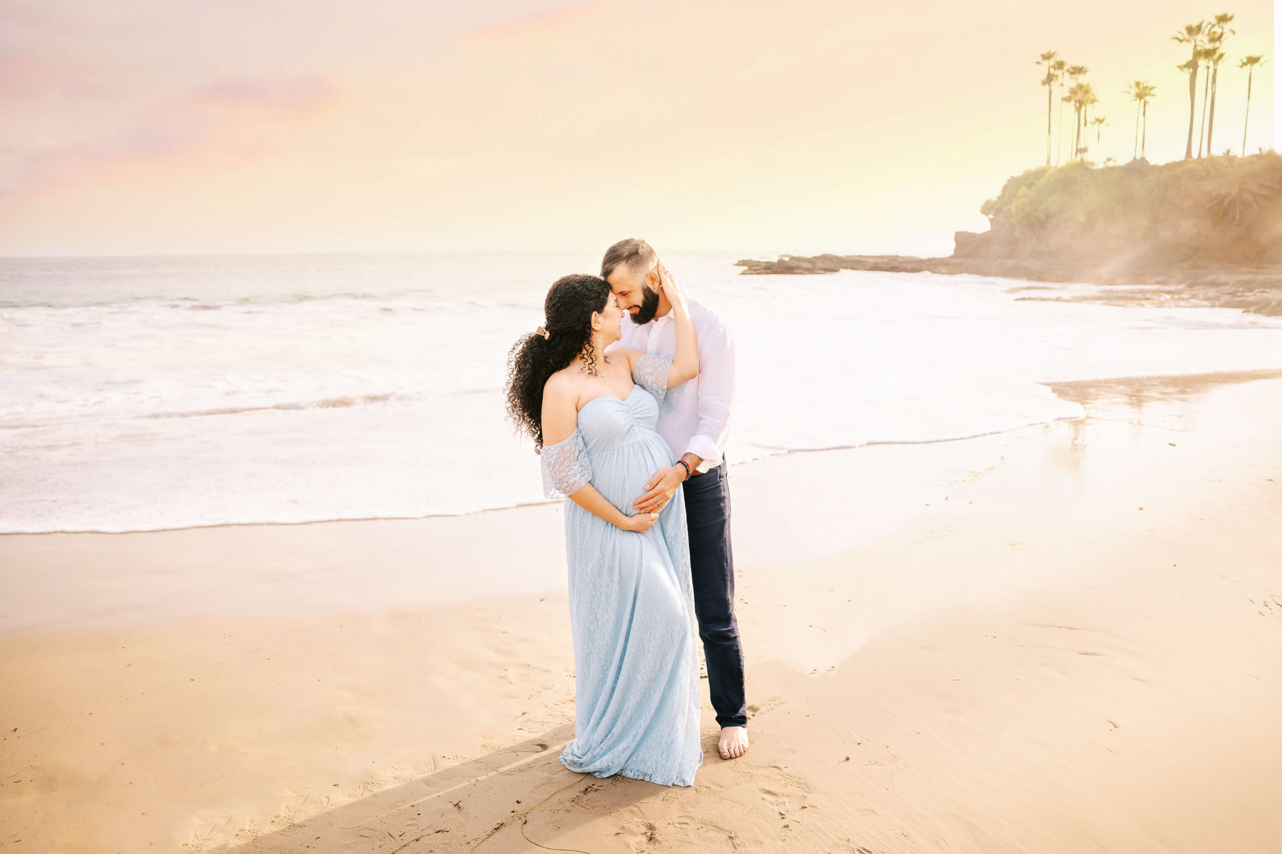 Couple embraced with touching foreheads during maternity session in Laguna Beach, CA by Ashley Nicole Photography.