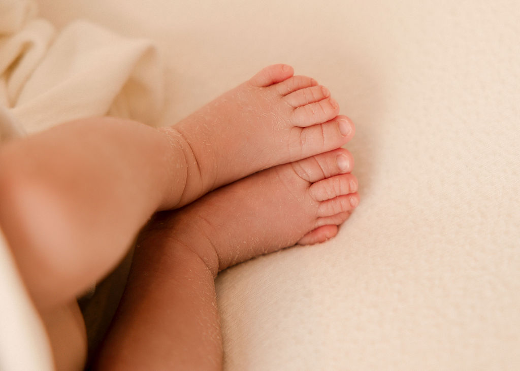 Details of a newborn baby's feet on a white bed after meeting long beach pediatricians