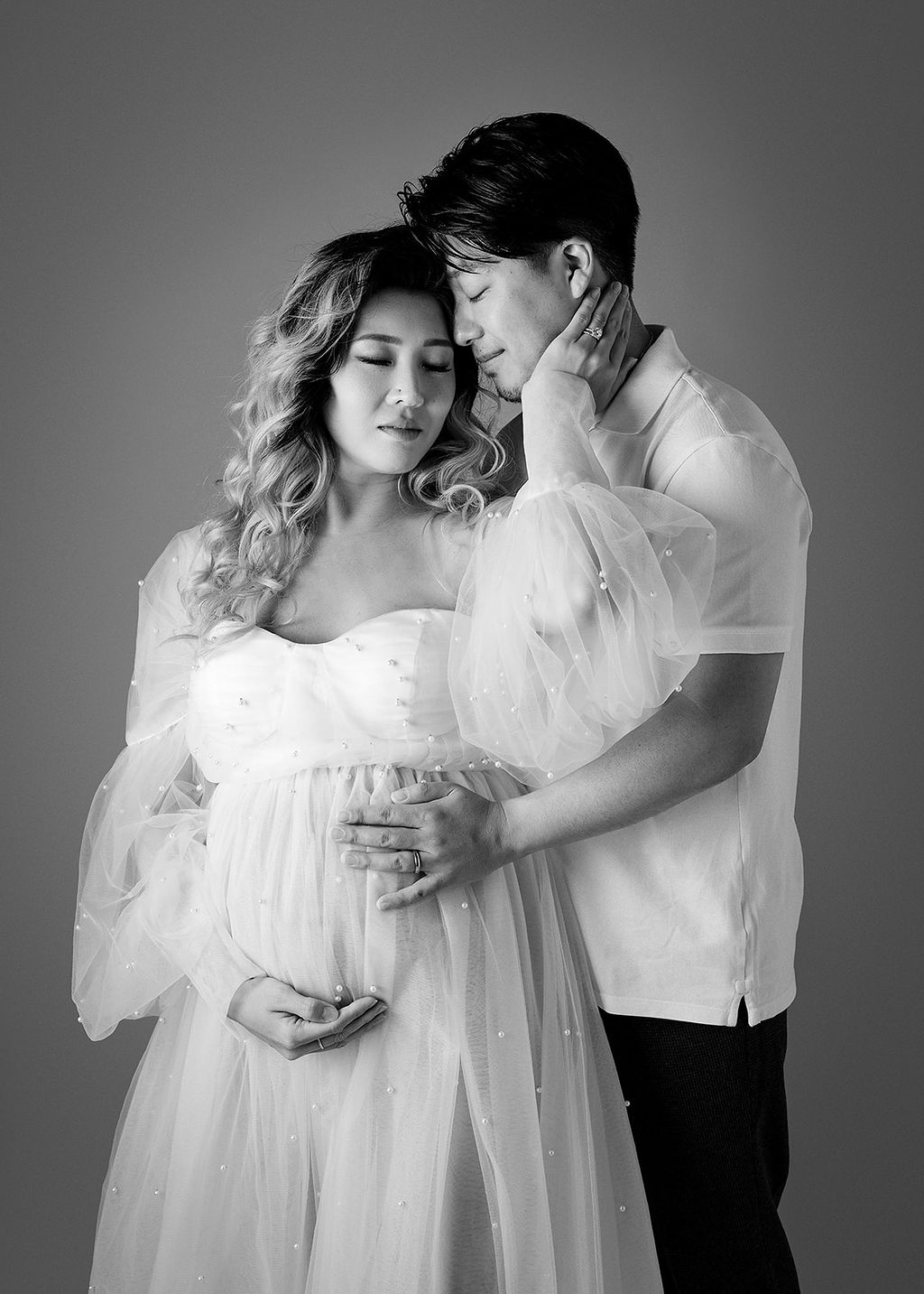 A happy expecting couple snuggles gently while standing in a studio after meeting Boise Midwives