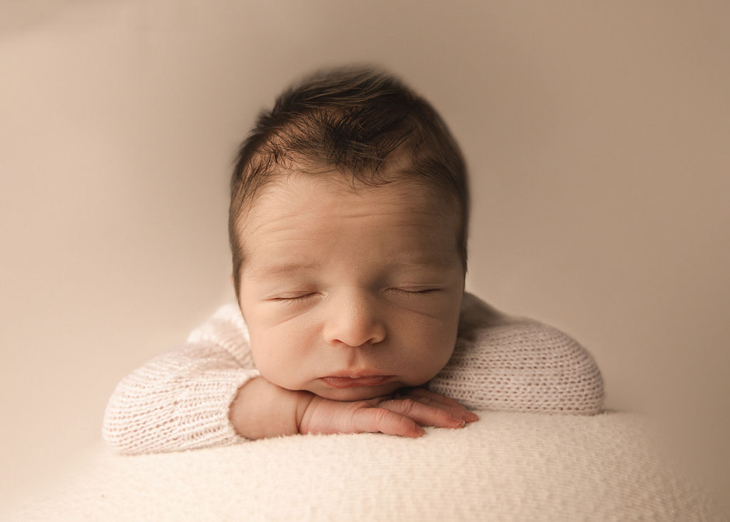 Details of a sleeping newborn baby resting its head on its hands